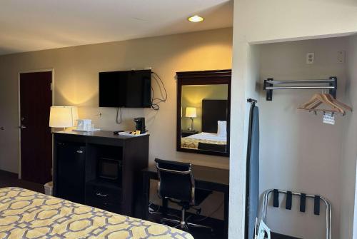 a bedroom with a bed and a desk and a mirror at Baymont by Wyndham Farmington in Farmington
