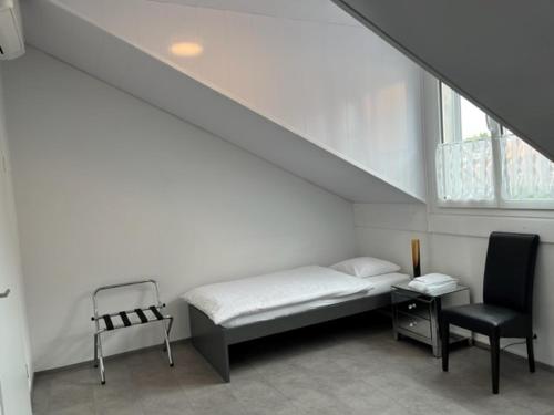 Hotel Hippel Krone في Kerzers: غرفة بيضاء بسرير وكرسي
