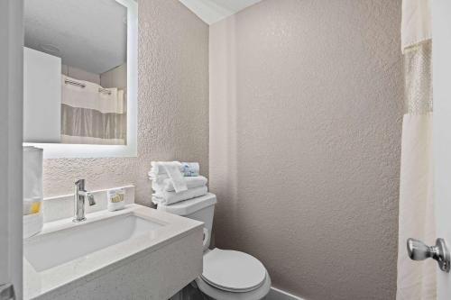 a white bathroom with a sink and a toilet at Super 8 by Wyndham Kissimmee-Orlando in Orlando