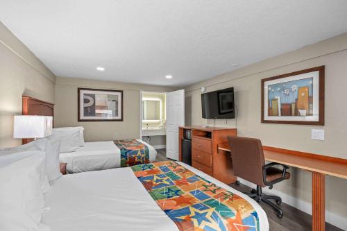 オーランドにあるTravelodge by Wyndham Kissimmee Orlandoのベッド2台とデスクが備わるホテルルームです。