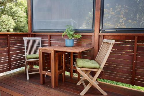 een houten tafel en twee stoelen op een terras bij Cosy hillside studio in Ocean Shores