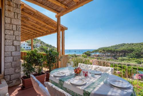 a table on the balcony with a view of the ocean at Case vacanza Barbatoja in Fetovaia