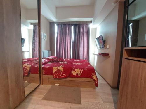 1 dormitorio con cama roja y espejo en Ilham Apartemen Batch 1, en Serang