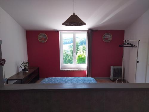 a red room with a bed and a window at La Coste Blanque in Montaut