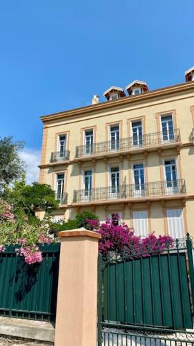 a building with a green fence and purple flowers at Loft apartment at Villa Leonie in Hyères