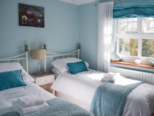 a blue bedroom with two beds and a window at Seventh Heaven in Bagby