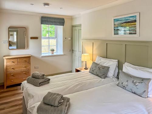 a bedroom with a large white bed with two pillows at Kingfisher Cottage in Kirkton of Airlie