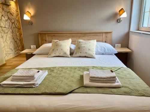 a large white bed with two towels on it at Fantažija Apartment in Brodarica