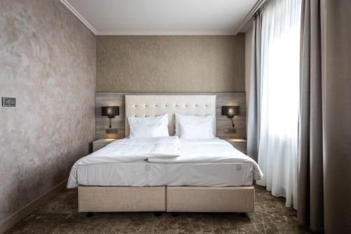a bedroom with a white bed and a window at HOTEL EUROPA in Komárno