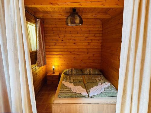 a small room with a bed in a wooden cabin at Babett Vendégház in Zánka