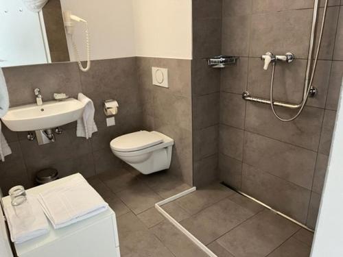 a bathroom with a toilet and a sink and a shower at Hotel Hippel Krone in Kerzers