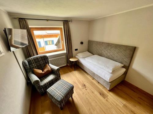 a small bedroom with a bed and a chair at Haus Schrofenstein in Lech am Arlberg