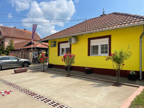 a yellow house with trees in a parking lot at Vila Sunce Morovic in Morović