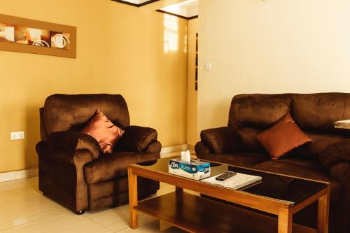 a living room with two chairs and a coffee table at Highlands Suites Hotel and Apartments in Kigali