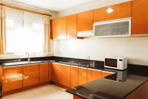 a kitchen with wooden cabinets and a microwave at Highlands Suites Hotel and Apartments in Kigali