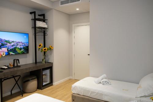 a living room with a bed and a tv on a wall at Bee Hotel in Vlorë