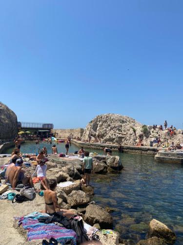 a group of people sitting on the rocks at a beach at Le Cabanon du Vallon des Auffes in Marseille