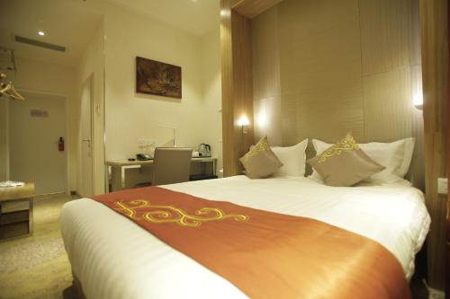 a bedroom with a large white bed with gold decorations at H9 Hotel Nine Ulaanbaatar in Ulaanbaatar