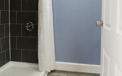 La salle de bains est pourvue d'une douche avec un rideau de douche blanc. dans l'établissement Glenghorm Beach Resort, à Ingonish