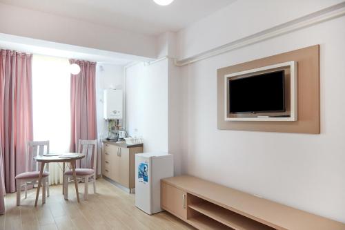um quarto de hotel com televisão, mesa e cadeiras em Excelsior apartaments 2 mamaia nord em Mamaia Nord – Năvodari
