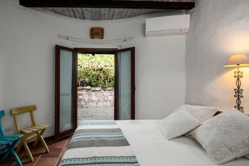 a white bedroom with a bed and a window at Villa Ponente in Golfo Aranci