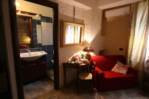 a bathroom with a red couch and a sink at B&B Alfrantoio Valderice in Valderice