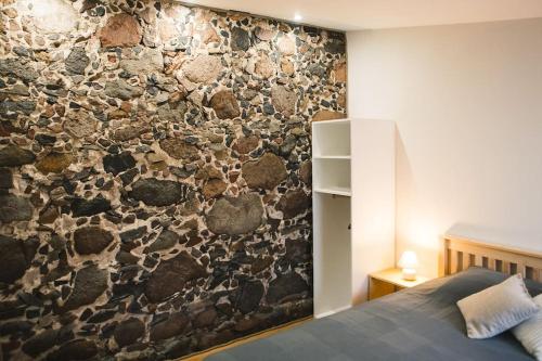 een slaapkamer met een stenen muur en een bed bij Aizpuri Rose View in Nīca