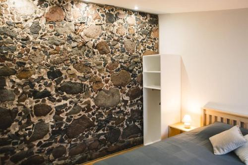 a bedroom with a stone wall with a bed at Aizpuri Rose View in Nīca