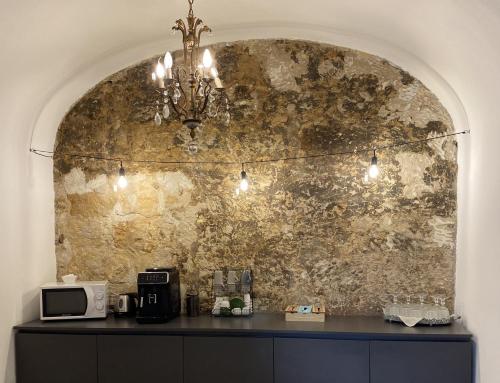 Settegrana Suite con vasca idromassaggio في شينيسي: ثريا معلقة على كونتر مع جدار