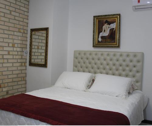 a bedroom with a large white bed with a brick wall at Casa MAgdeburg II - Central e completa in Pomerode