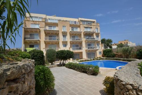 ein Gebäude mit einem Pool vor einem Gebäude in der Unterkunft Gozo Spacious Apartment with Large Communal Pool in Qala