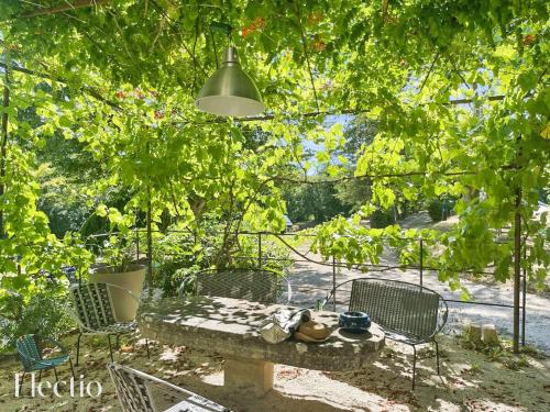 a patio with a table and chairs under trees at Parenthèse en Luberon in Rustrel