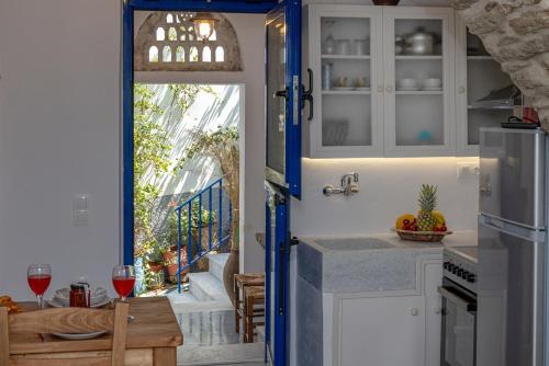 a kitchen with a door open to a balcony with a table and wine glasses at Βόλτα Καλλονή studio (Volta Kalloni) in Kalloni Tinou