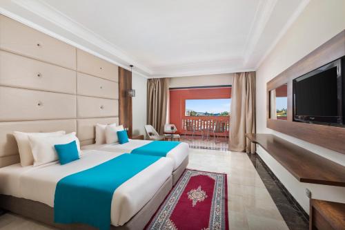 um quarto de hotel com duas camas e uma televisão de ecrã plano em Pickalbatros Aqua Fun Club All inclusive em Marraquexe