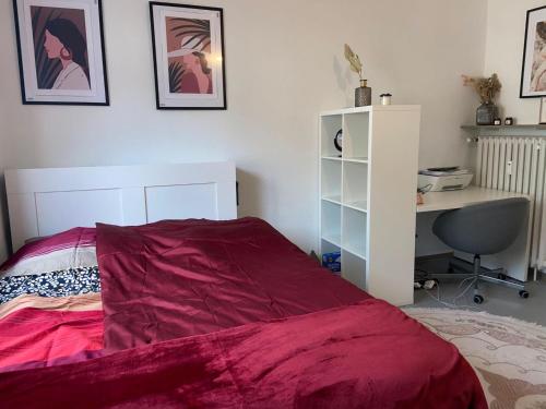 a bedroom with a bed with a red comforter and a desk at Adler Apartment in Cologne