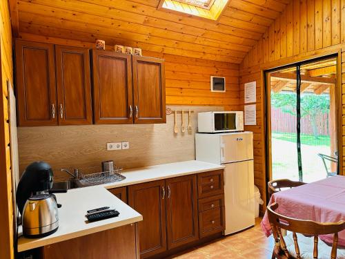 eine Küche mit Holzschränken und einem Kühlschrank in der Unterkunft Babett Vendégház in Zánka