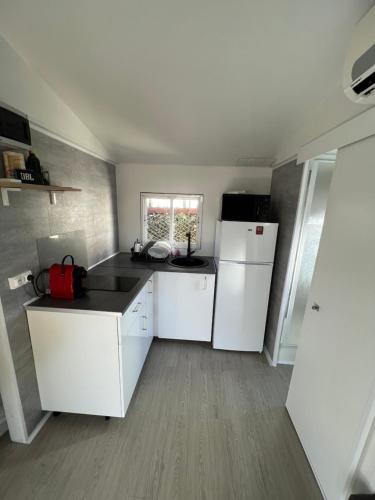 Il comprend une cuisine équipée de comptoirs blancs et d'un réfrigérateur blanc. dans l'établissement Europcamping, à Fréjus