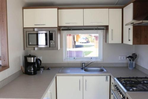 a kitchen with white cabinets and a sink and a window at Luxusmobilheim Seehund am Kransburger See 551 in Kransburg