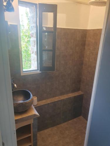 une salle de bain avec un lavabo et une fenêtre dans l'établissement La Magnanerie du Castanet, à Banne