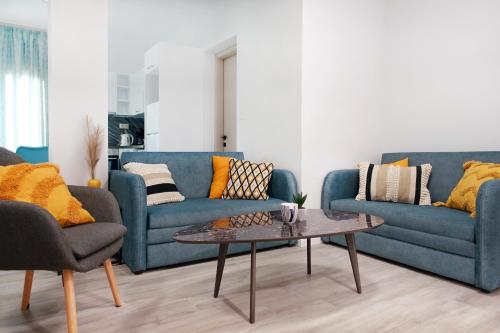 a living room with two blue couches and a coffee table at Okean Apartments in Ierissos