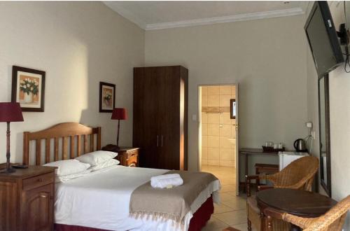 - une chambre avec un lit, une table et une télévision dans l'établissement Schoongezich Guesthouse, à Pretoria