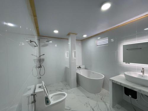 Thoddoo White Sand Inn في ثودو: حمام مع حوض ومرحاض وحوض استحمام