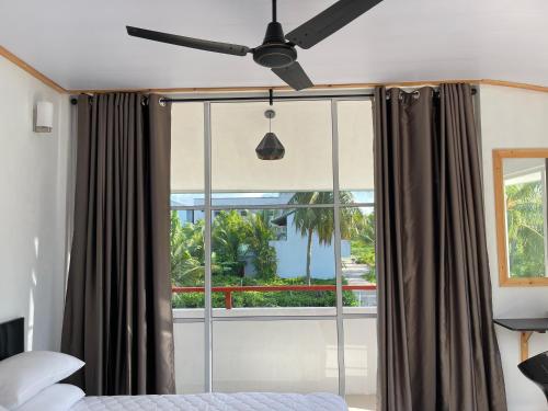 a bedroom with a ceiling fan and a window at Dacha Thoddoo White Sand in Thoddoo