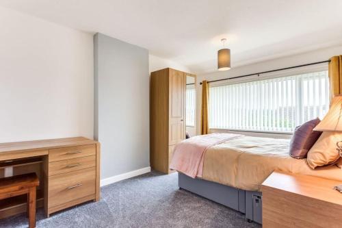 um quarto com uma cama, uma secretária e uma janela em Delightful Garforth Home em Garforth