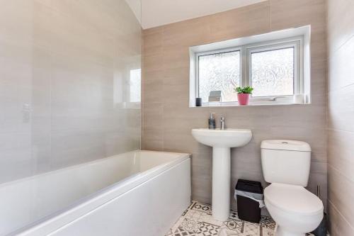 a bathroom with a toilet and a sink and a bath tub at Delightful Garforth Home in Garforth