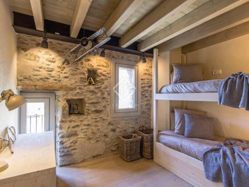 een slaapkamer met 2 stapelbedden en een stenen muur bij Villa Age in Puigcerdà