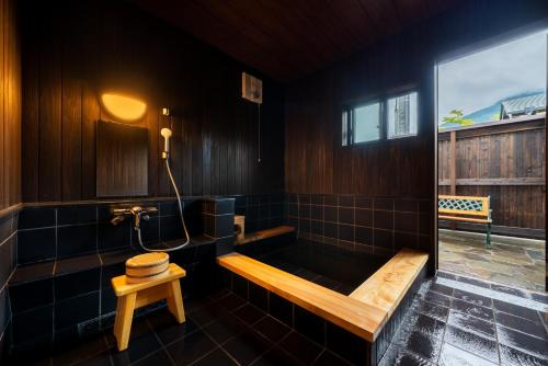 a bathroom with a tub with a bench and a window at 由布の里 旅荘 牧場の家 Ryoso Makibanoie in Yufuin