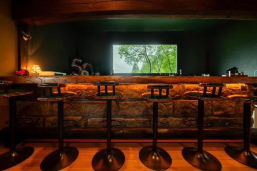 a bar with four stools in front of a counter at 由布の里 旅荘 牧場の家 Ryoso Makibanoie in Yufuin