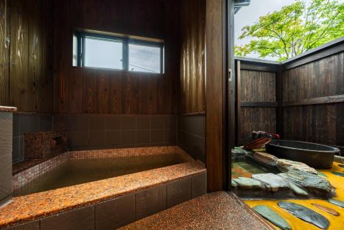 a bathroom with a bath tub with a window at 由布の里 旅荘 牧場の家 Ryoso Makibanoie in Yufuin