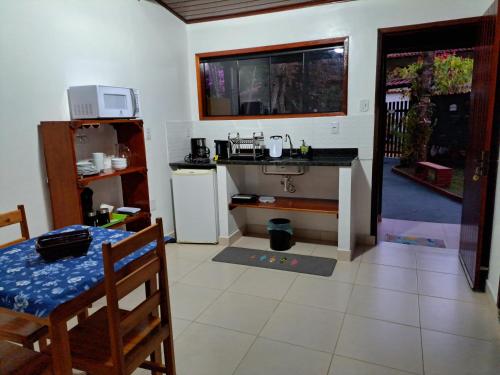 a kitchen with a table and a sink and a refrigerator at Recanto das Flores Lofts - Ilha Grande Rj in Abraão